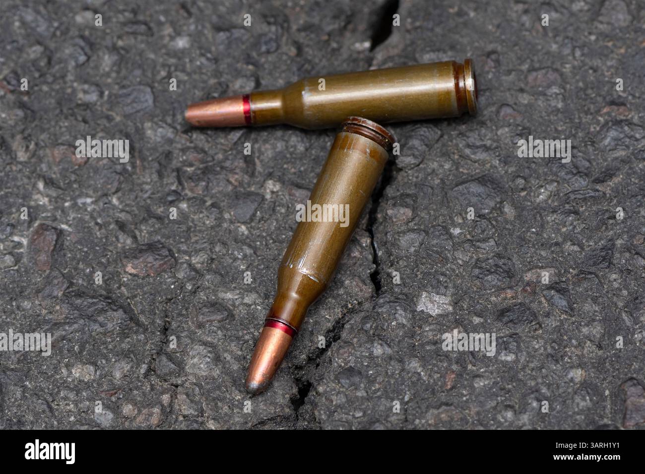 Zwei Patronen mit einer Kugel mit einer versetzten Mitte liegen auf einem dunklen texturalen Hintergrund, selektiver Fokus, Konzept: Verbotene expansive Kugeln, der Krieg Stockfoto