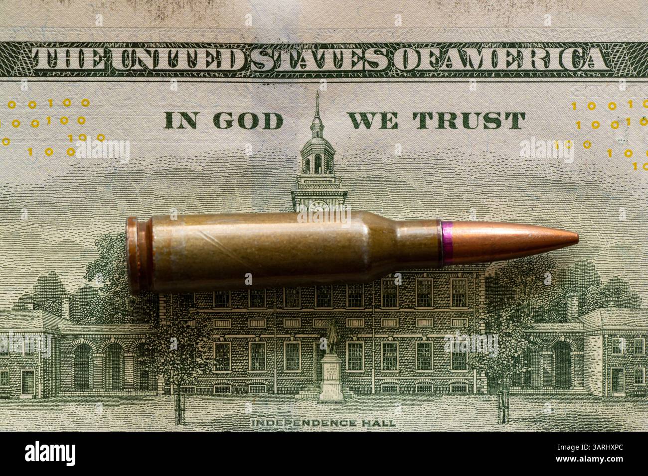 Die Kugel liegt auf einem Dollarschein, und der Text auf dem Gesetz steht in Gott, wir vertrauen, Geld für Waffen Stockfoto