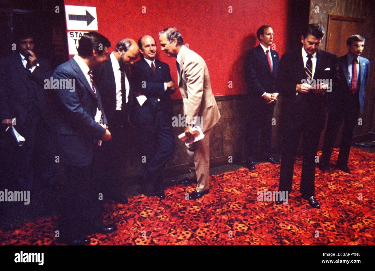 Juli 1983; Washington, DC, USA; der 40. US-Präsident (1981–89) RONALD WILSON REAGAN (auch bekannt als der „Great Communicator“) wurde am 6. Februar 1911 in Tampico, Illinois, geboren. Reagan leidet an der Alzheimer-Krankheit, einer degenerativen Erkrankung, die das Gehirn beeinflusst und Gedächtnisverlust und Demenz verursacht. . IM BILD: Präsident Reagan bereitet sich auf eine Rede in einem DC-Hotel vor, während sich Stabschef JIM BAKER (leichte Anzüge), Stabschef MIKE DEVER (Arme gefaltet) und Director of Communications ED ROLLINS zu Gesprächen zusammenscharen. Die anderen Männer sind Geheimdienstschutz. (Bild: Michael Evans/ZUMAPRESS.com) Stockfoto