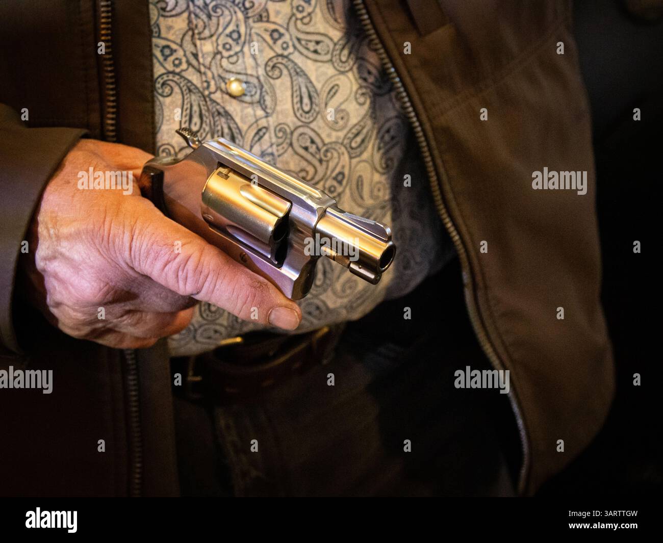 Ein Mann hält einen Revolver an seiner Seite. Stockfoto