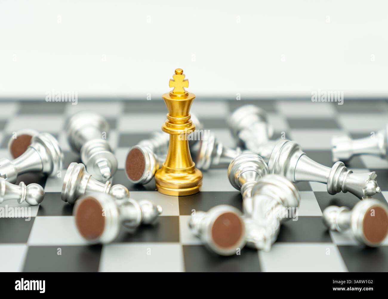 Goldenes Königschachteil gewinnt über liegendes silbernes Stück auf weißem Hintergrund. Stockfoto