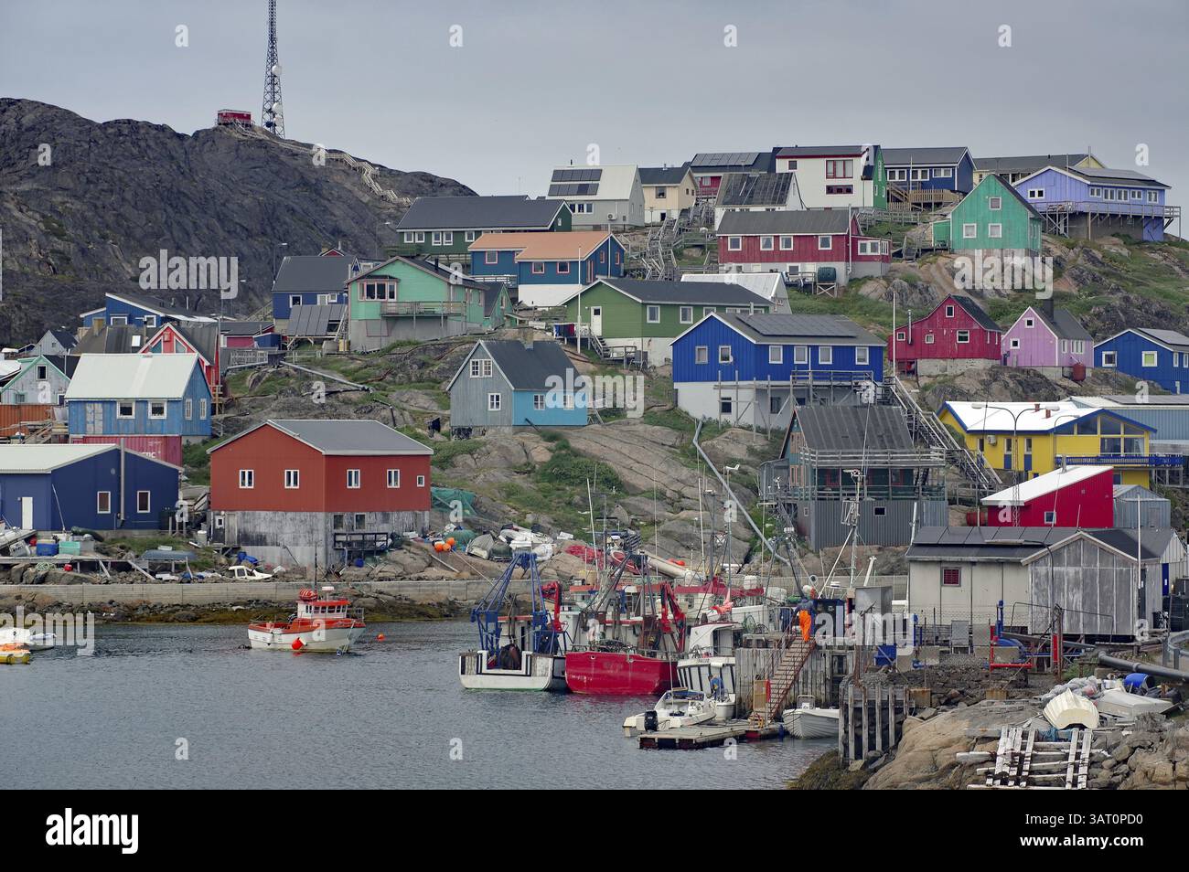 Farbenfrohe Häuser auf einem Hügel mit Fischerbooten im Hafen und bewölktem Himmel, Maniitsoq, Grönland, Dänemark, Nordamerika Stockfoto