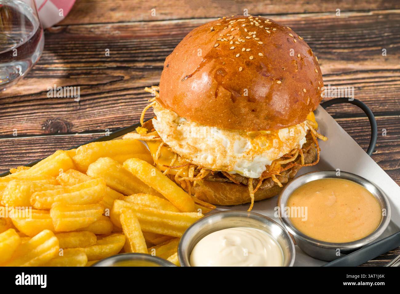 Eierburger mit knusprigen Kartoffeln serviert mit Pommes und Saucen Stockfoto