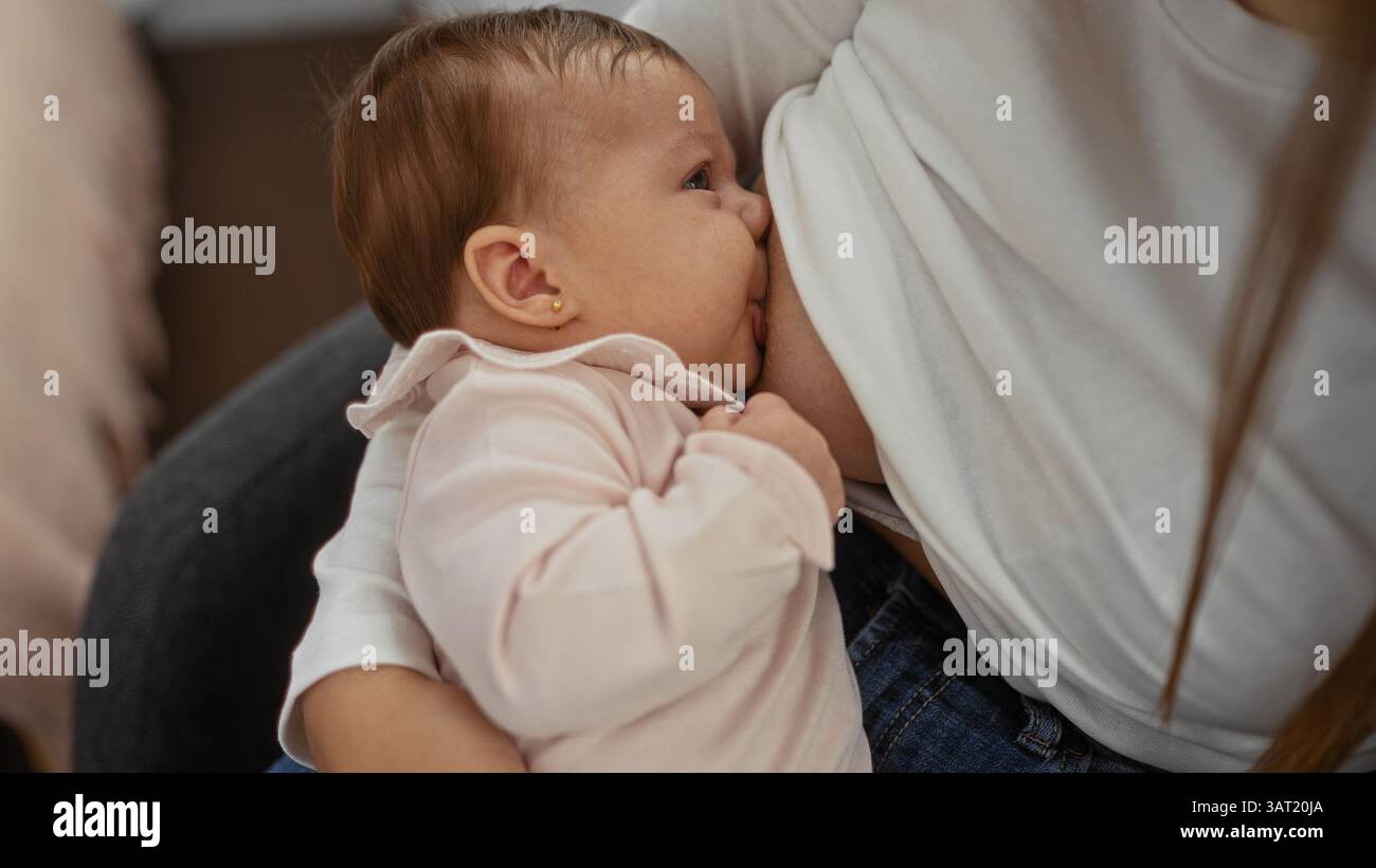Frau, die ihr Kind in einem Haus stillt, zeigt eine pflegende Bindung in einer intimen Umgebung mit Liebe und Komfort. Stockfoto