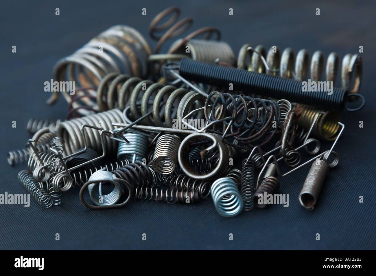 Viele kleine Federn unterschiedlicher Größe liegen auf einem Haufen vor schwarzem Hintergrund. Stockfoto