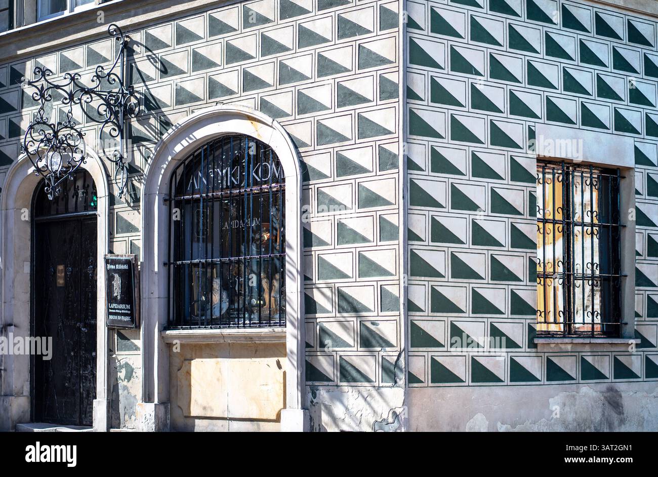 Ein Eckgebäude mit einer einzigartigen geometrischen Fassade mit grünen und weißen Rautenmustern. Der Eingang hat ein kunstvoll verziertes schmiedeeisernes Schild und ist verschlossen Stockfoto