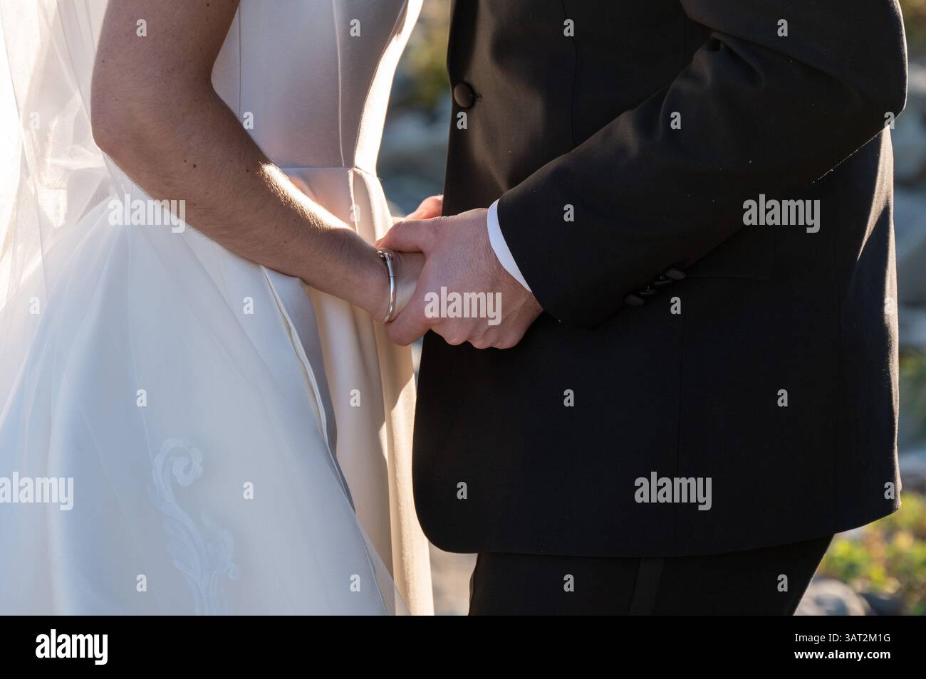 Braut und Bräutigam halten Hände im Sonnenlicht während der Hochzeitszeremonie Stockfoto