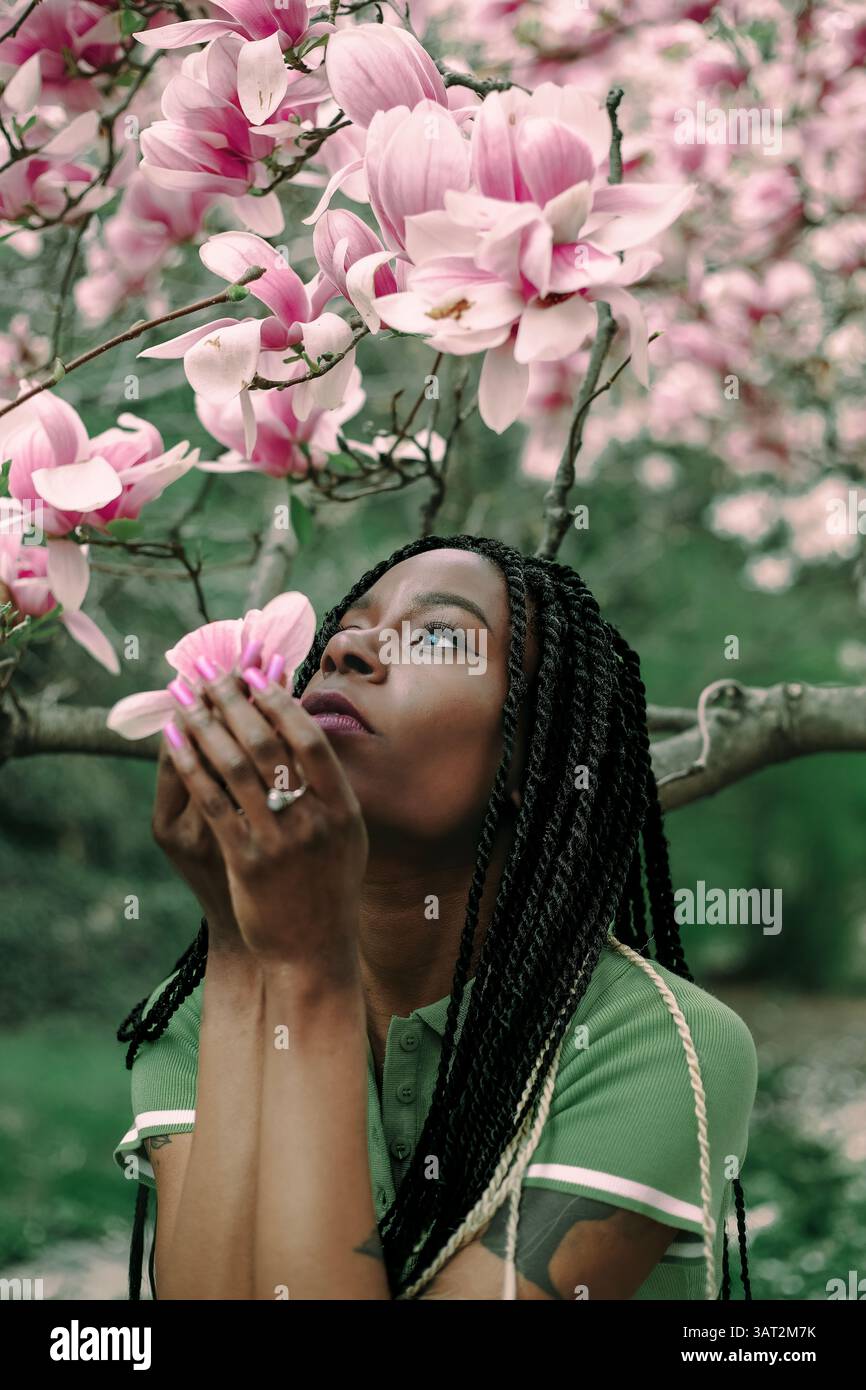 Eine schöne schwarze Frau unter einem blühenden Magnolienbaum Stockfoto
