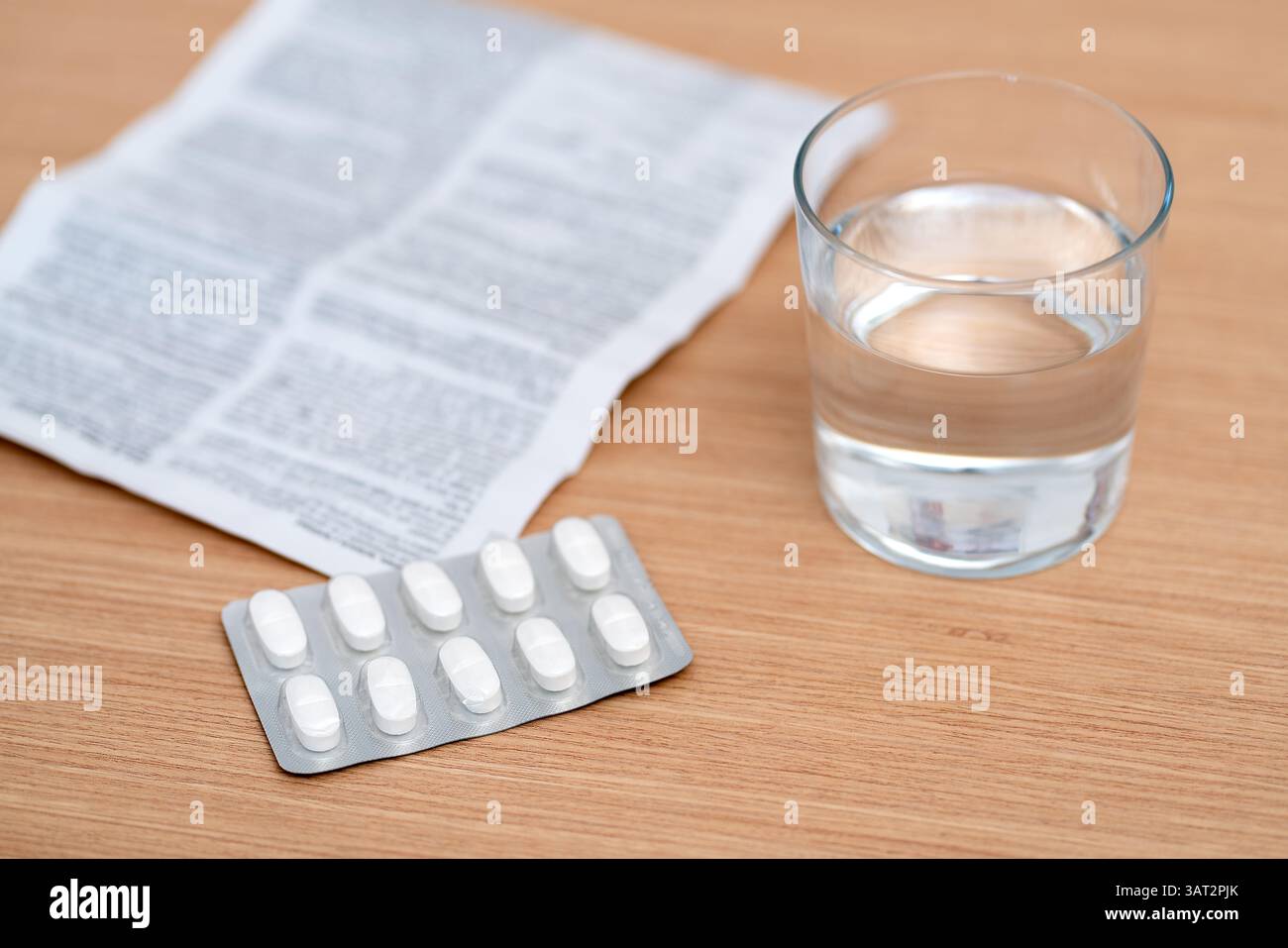 Weiße Kapseln, Gläser Wasser und ein Rezept werden auf einen Tisch gestellt. Stockfoto