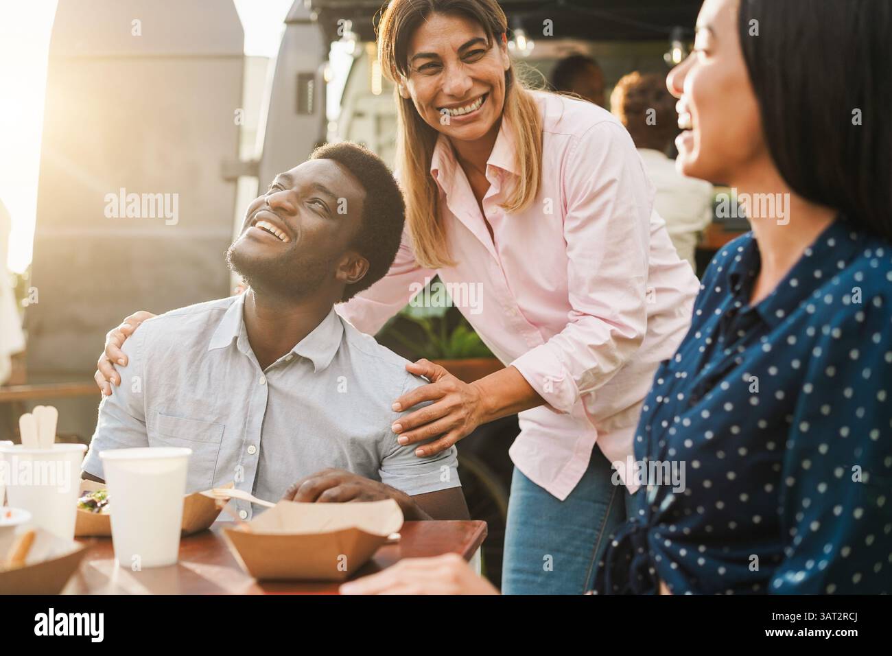 Multirassische Menschen essen im Food Truck Restaurant im Freien - Sommer Lifestyle und Dinner Konzept - Fokus auf afrikanisches Männergesicht Stockfoto