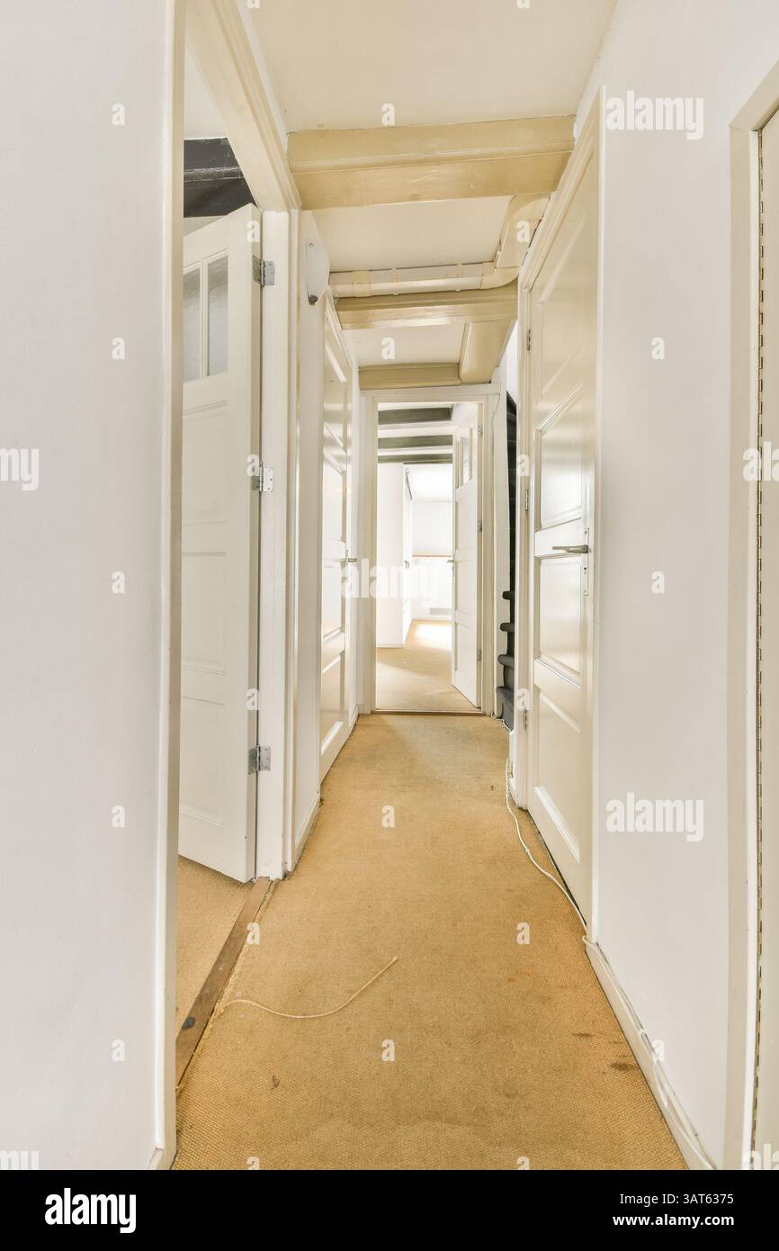 Ein geräumiger Innenkorridor mit mehreren Türen, hellen Wänden und einem neutralen Teppich, der die offene Atmosphäre des Raumes unterstreicht. Stockfoto