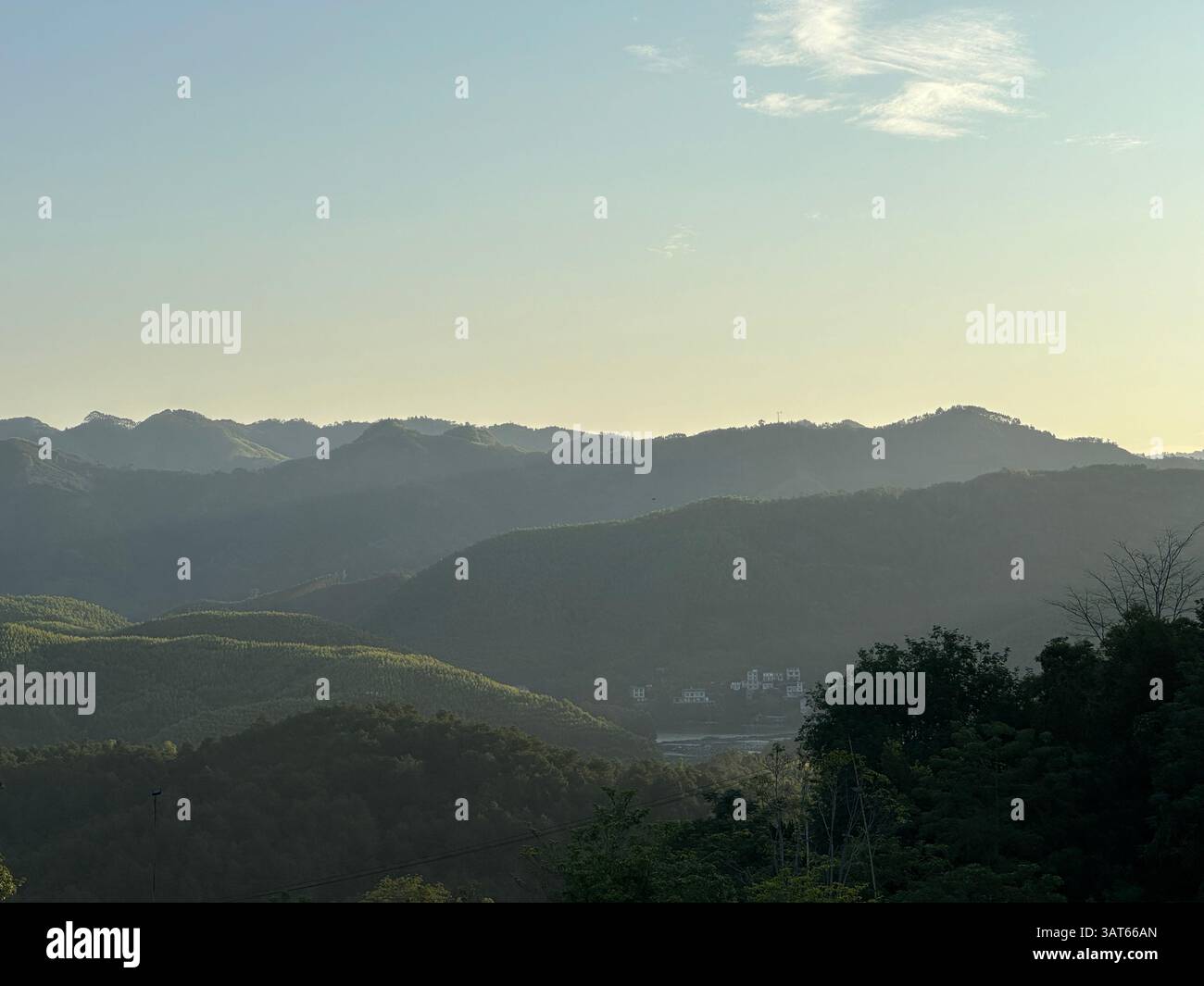 Die Berge erstrecken sich am Horizont unter einem wunderschönen, abgestuften Himmel bei Sonnenuntergang in Guangxi, China. - Smartphone-aufgenommenes Stockfoto