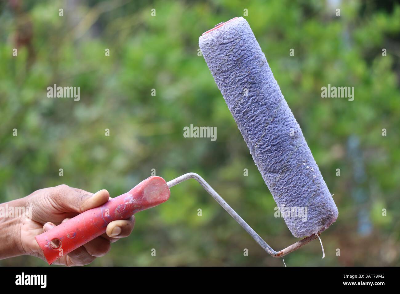 Gebrauchte Malerwalzenmaschine zum Lackieren flacher Oberflächen wie Wände, die im Freien an der Hand gehalten werden Stockfoto