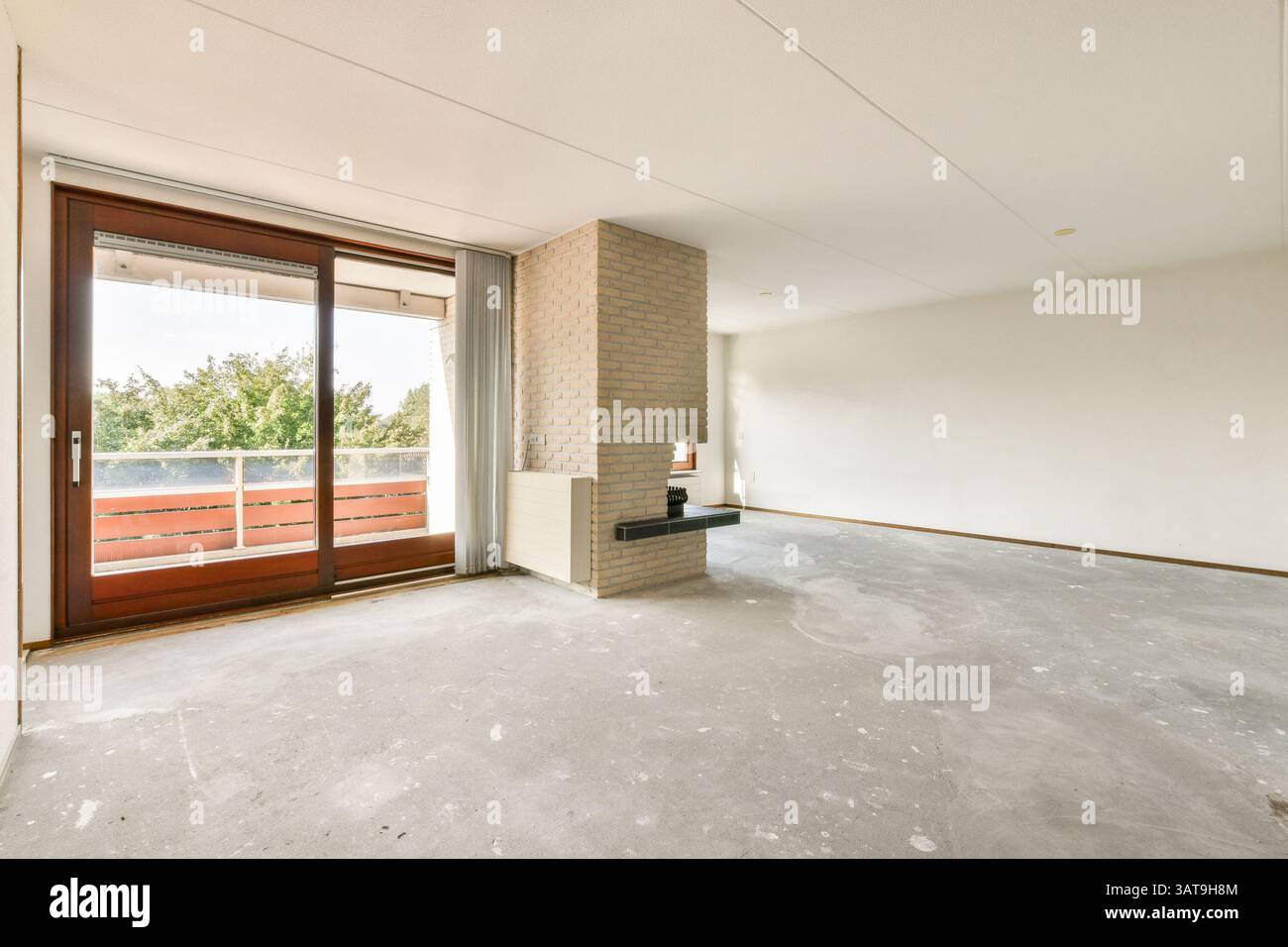 Das helle und luftige, moderne Apartment verfügt über große Fenster, neutrale Wände und eine offene Einrichtung, die für ein ruhiges Wohnumfeld sorgt. Stockfoto