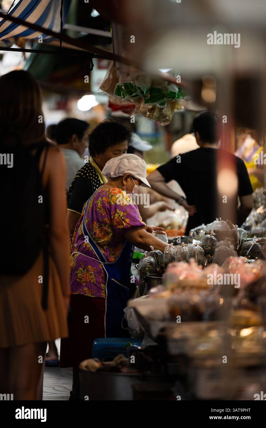 Lokaler Anbieter, der Waren auf einem traditionellen Markt in Bangkok, Thailand, verkauft. Die Szene fängt das tägliche Leben mit satten Farben und authentischer Atmosphäre ein. Stockfoto