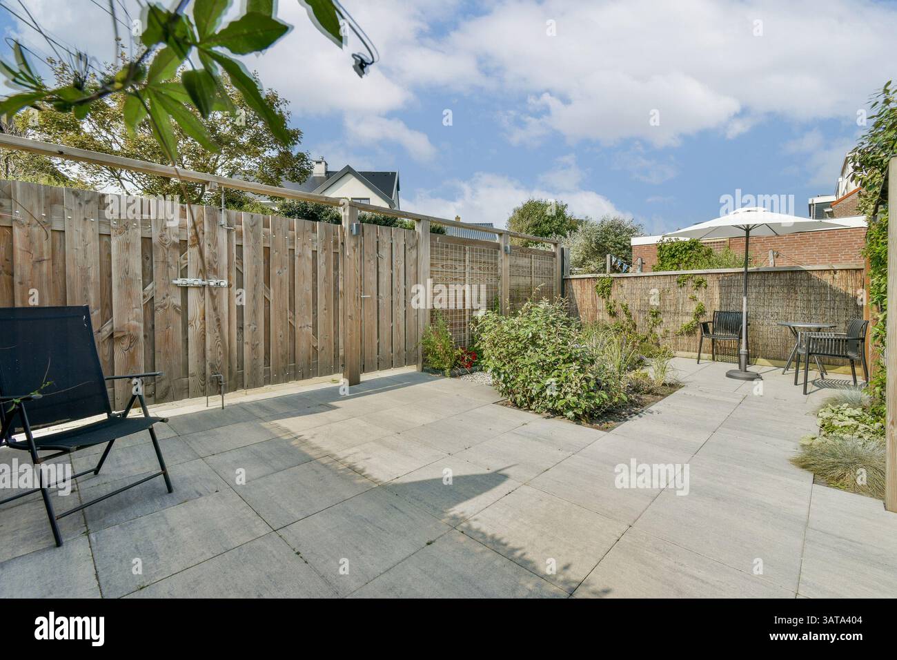 Eine ruhige Terrasse im Freien mit Holzzäunen, Steinböden und üppigen Pflanzen, perfekt für Entspannung oder gesellschaftliche Zusammenkünfte. Stockfoto