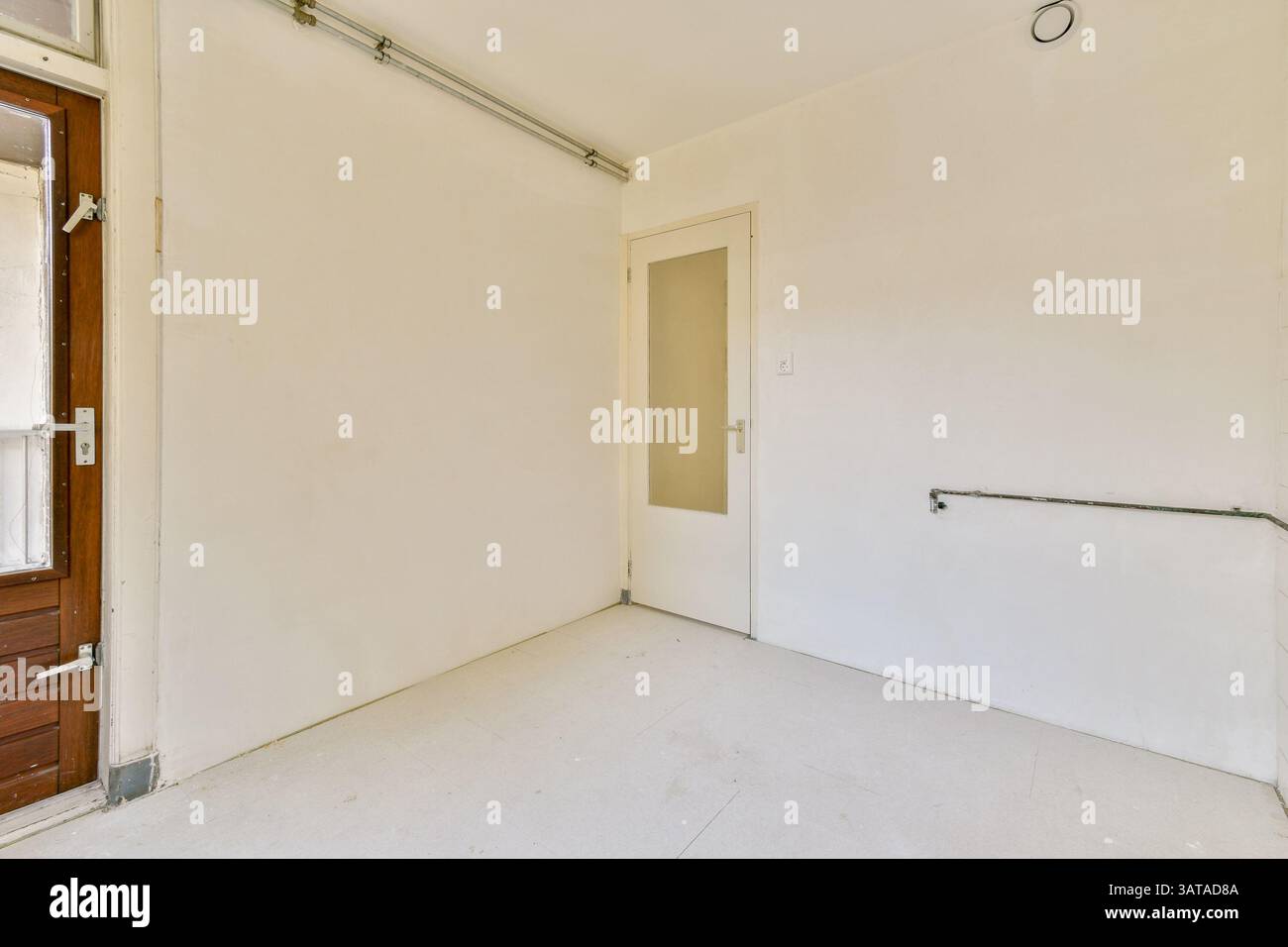 Ein einfacher, sauberer Innenraum mit einfacher Wand und offener Tür. Die Ästhetik reflektiert Minimalismus mit neutralen Tönen. Stockfoto