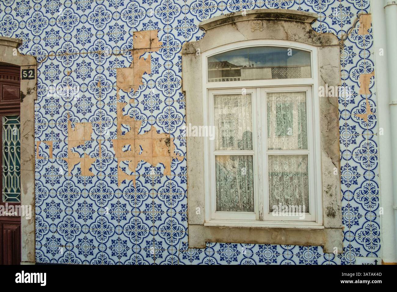 Fenster an einer Hauswand mit gefliester Fassade an der einige Fliesen beschädigt sind in der Altstadt von Tavira, Algarve, Portugal in der Altstadt von Tavira *** Fenster an einer Hauswand mit einer gekachelten Fassade, an der einige Fliesen beschädigt sind, in der Altstadt von Tavira, Algarve, Portugal in der Altstadt von Tavira Stockfoto