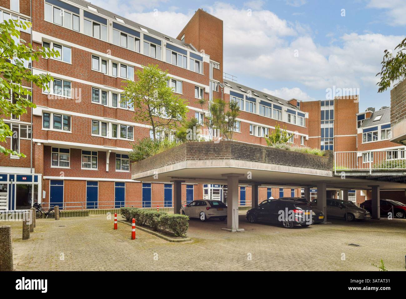Ein modernes Wohngebäude mit mehreren Fenstern, Grünanlagen und einer Tiefgarage. Das Design zeigt moderne Architektur und urbanes Leben. Stockfoto