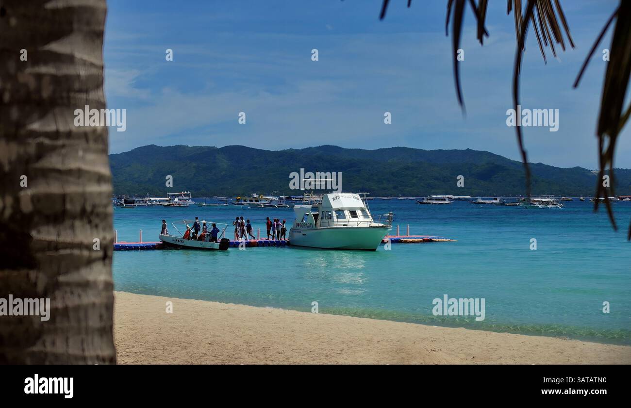 Urlauber überqueren eine schwimmende Plattform Pier zu und von einer Freizeitjacht auf der sehr beliebten Boracay Island, Philippinen. Stockfoto