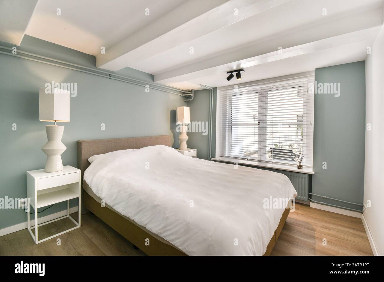 Ein wunderschön gestaltetes, modernes Schlafzimmer mit sanften Farben und minimalistischer Einrichtung schafft eine ruhige und einladende Atmosphäre, die perfekt zum Entspannen ist. Stockfoto