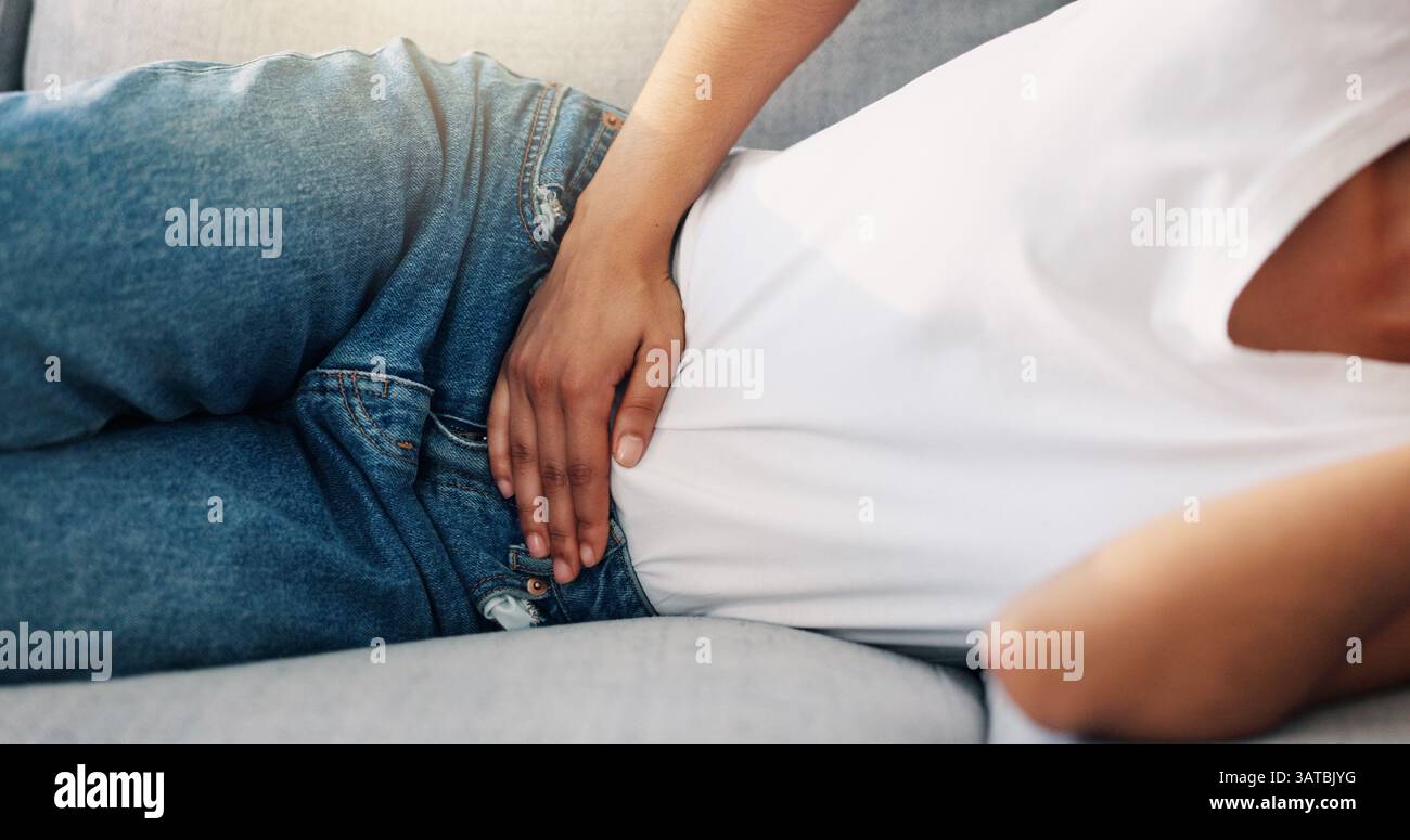 Frau, entspannen oder Hände auf Bauch mit Schmerzen, Menstruationskrämpfen oder Reizdarm Symptome zu Hause. Person, Unwohlsein oder Ruhe auf dem Sofa mit Periode, Bauchschmerzen oder Stockfoto