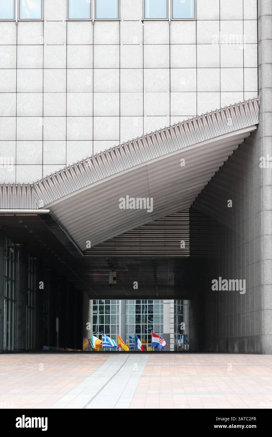 Modernes architektonisches Merkmal mit internationalen Flaggen unter einer geometrischen Fassade, die Design-Ästhetik und Symbolismus in globaler Einheit betonen. Stockfoto
