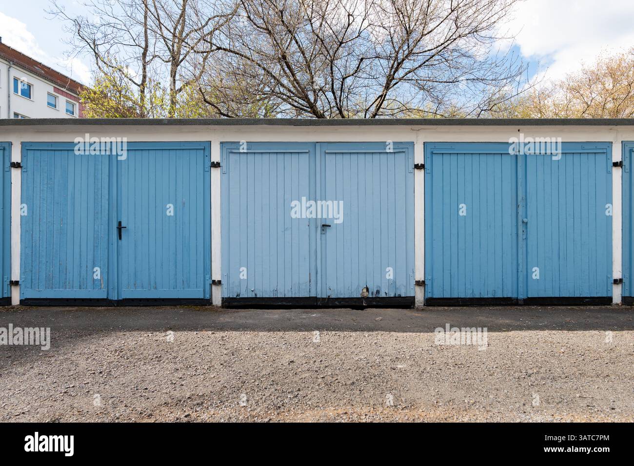 Deutsche Garageneinheiten in einer Reihe mit geschlossenen Doppeltüren. Gebäude außen mit blauen Toren. Abstellraum oder Parkplatz für ein kleines Auto. Stockfoto