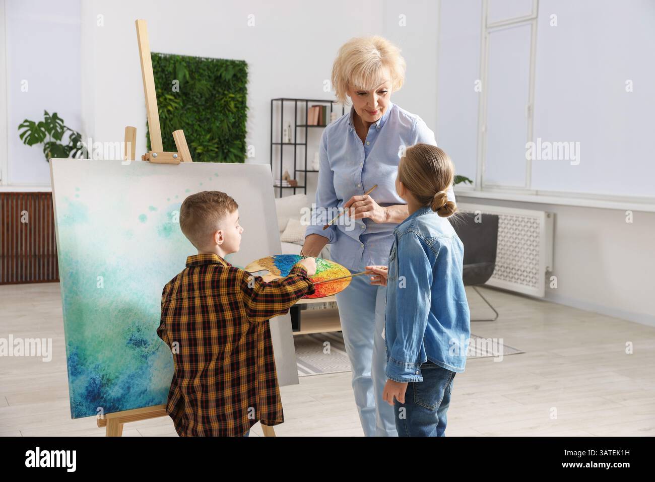 Großmutter und ihre Enkel malen zusammen zu Hause Stockfoto