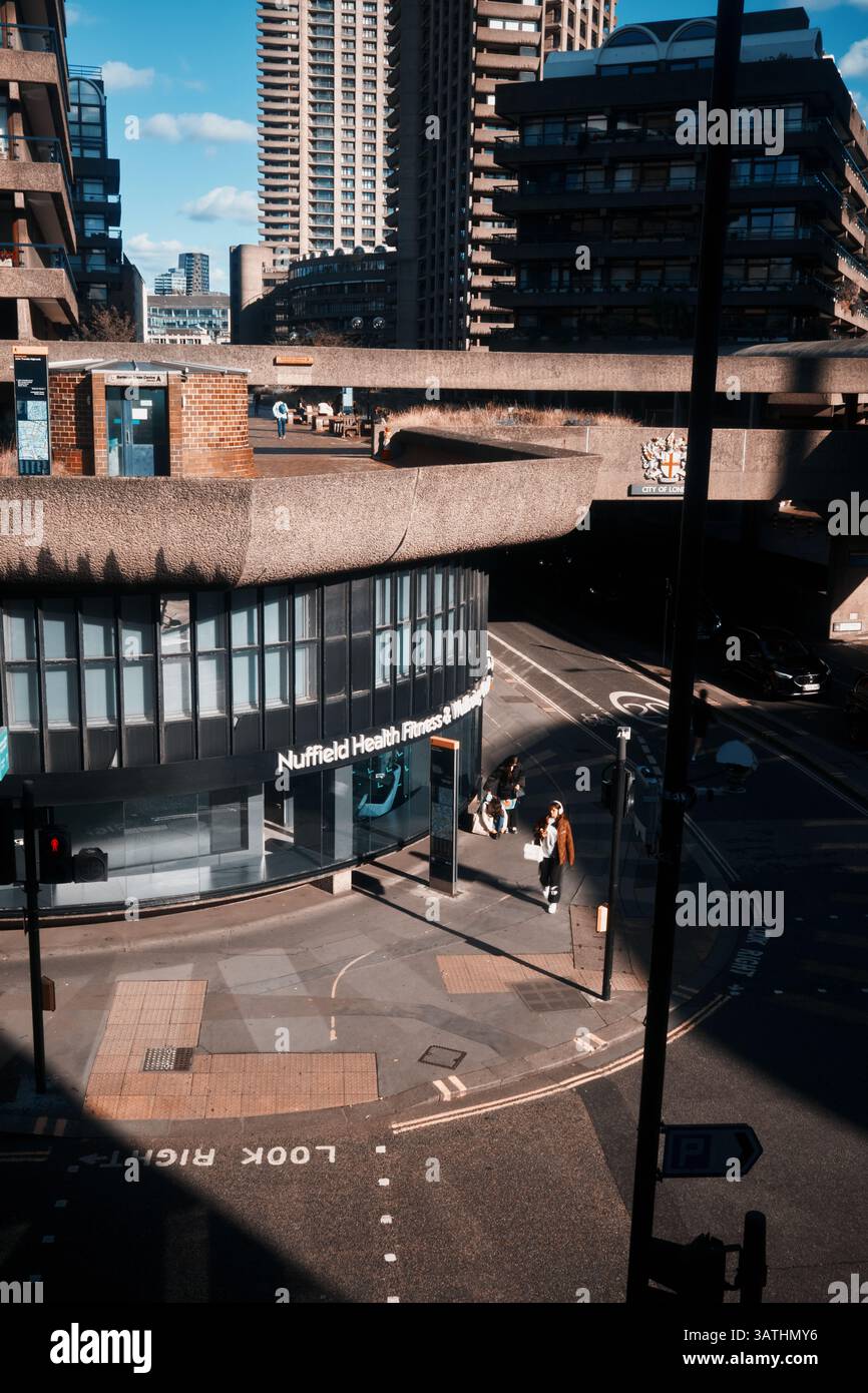 London, Großbritannien - 28. September 2024: Ein Blick auf die brutalistische Architektur des Barbican Estate und das Nuffield Health Centre mit Fußgängern in der Beech Stre Stockfoto