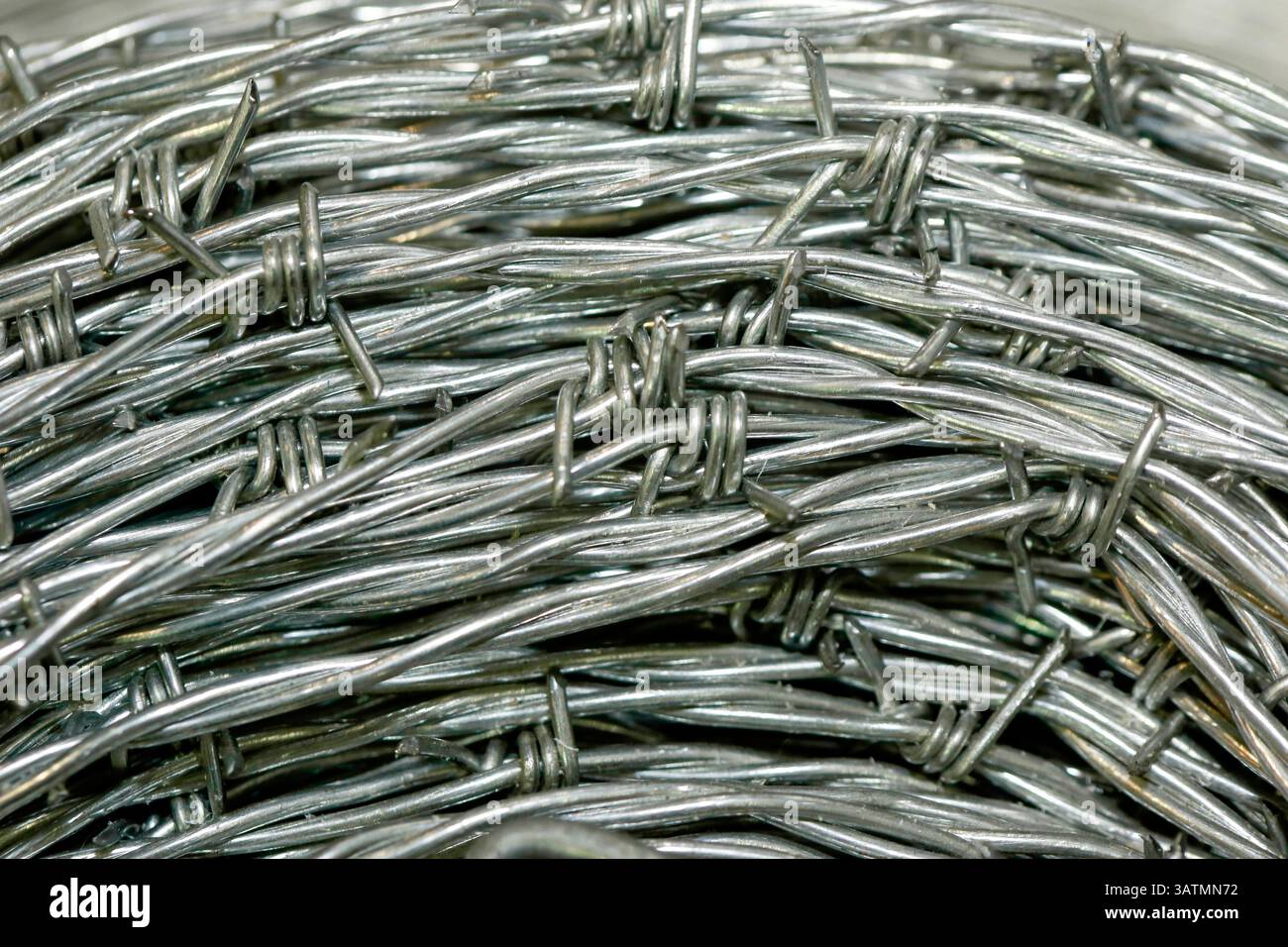 Nahaufnahme einer Stapelrolle aus glänzendem neuem Stacheldraht. Stockfoto