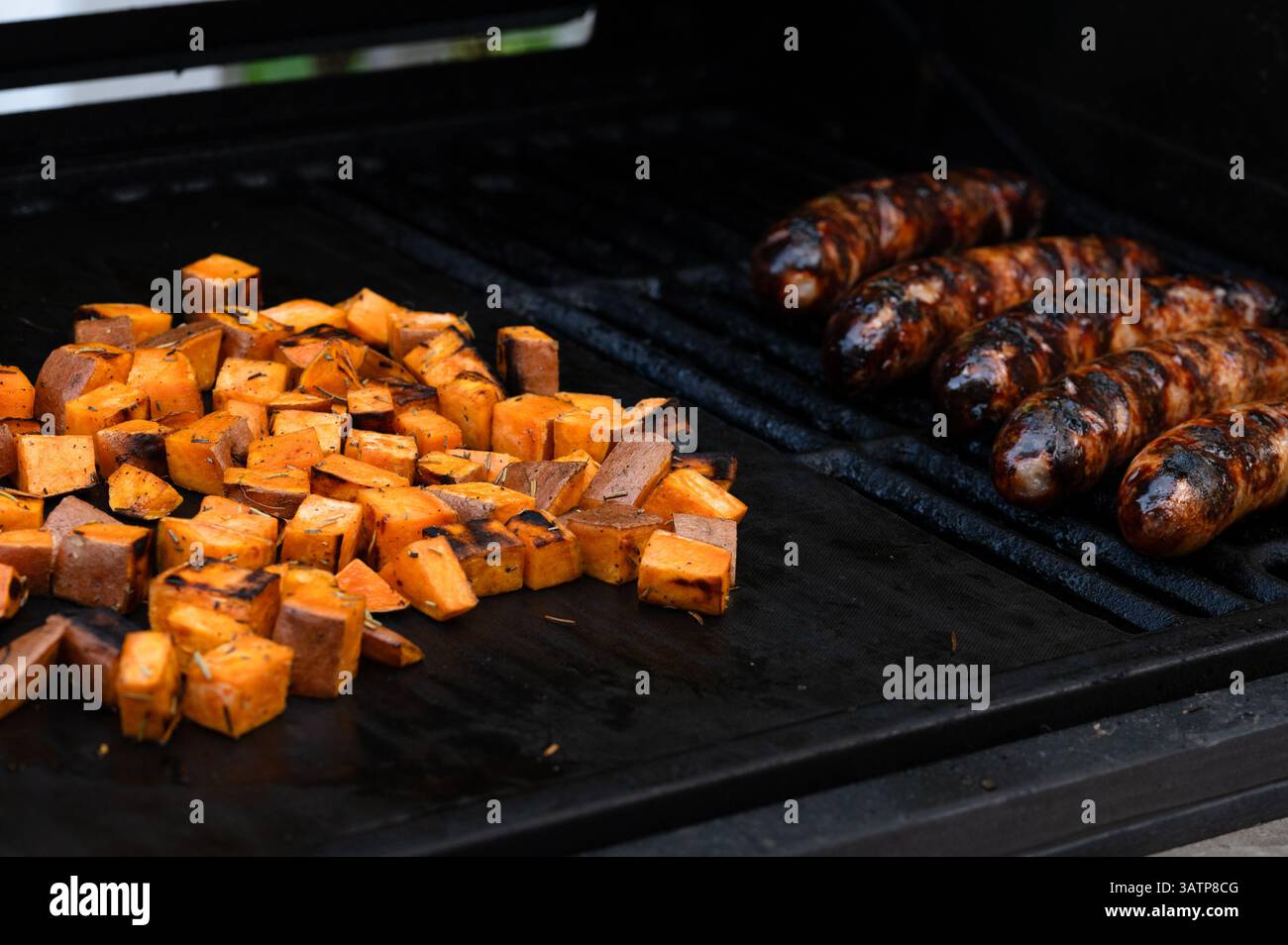 Süßkartoffeln und Braten, die auf einem Grill kochen Stockfoto