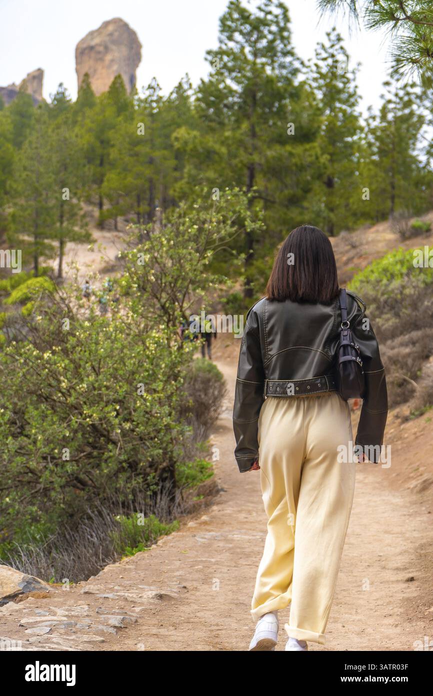 Junge Frau, die auf einem Waldweg in Richtung roque nublo, Vulkangestein auf gran canaria, den kanarischen Inseln, spanien, läuft Stockfoto