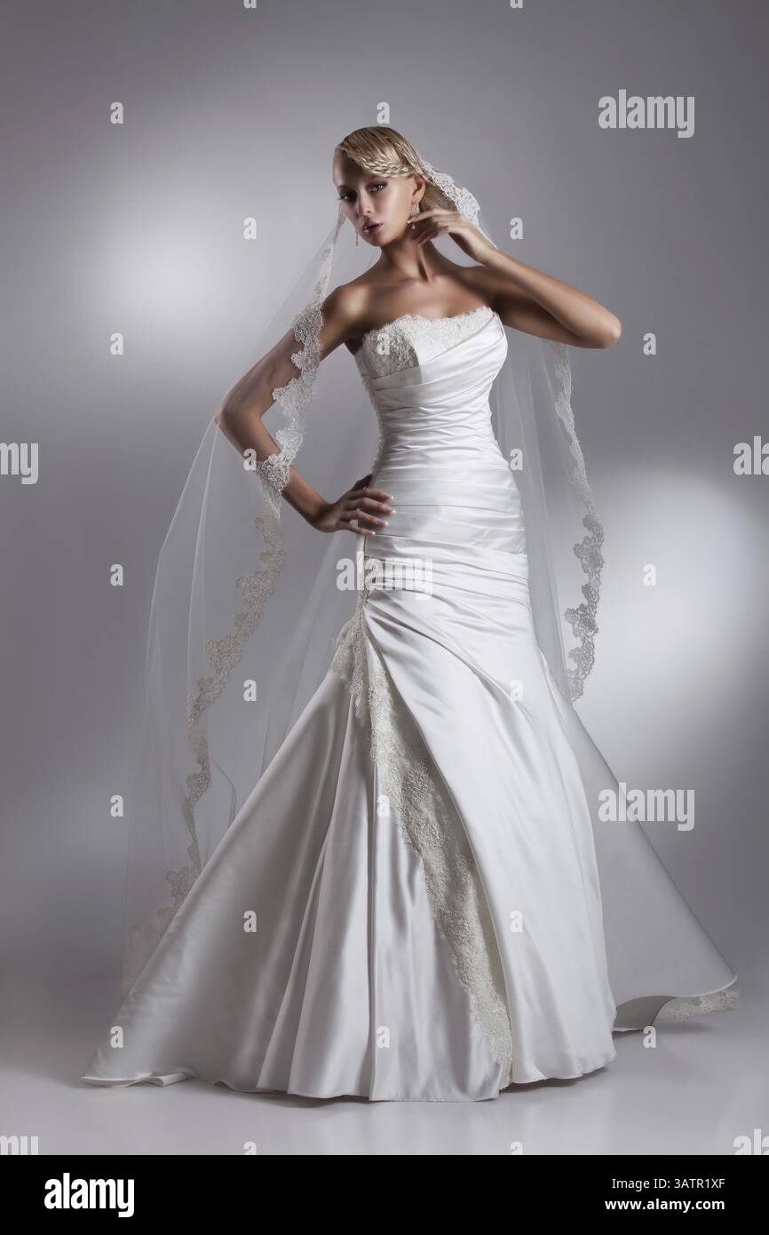 Junge schöne blonde Frau in einem Hochzeitskleid auf einem Atelierhintergrund Stockfoto