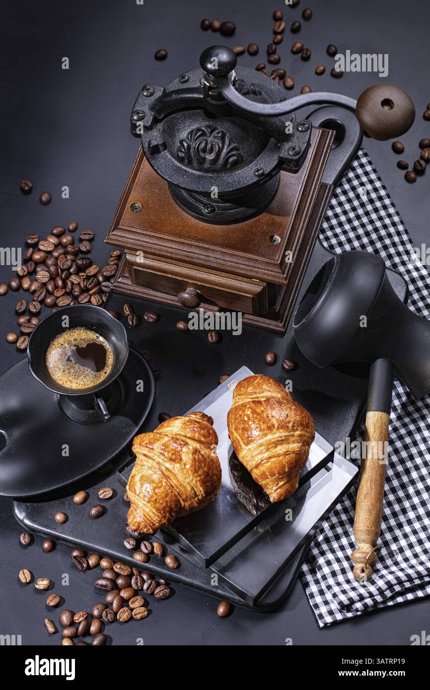 Tasse Kaffee, Mühle, Bohnen und Gebäck auf schwarzem Hintergrund Stockfoto