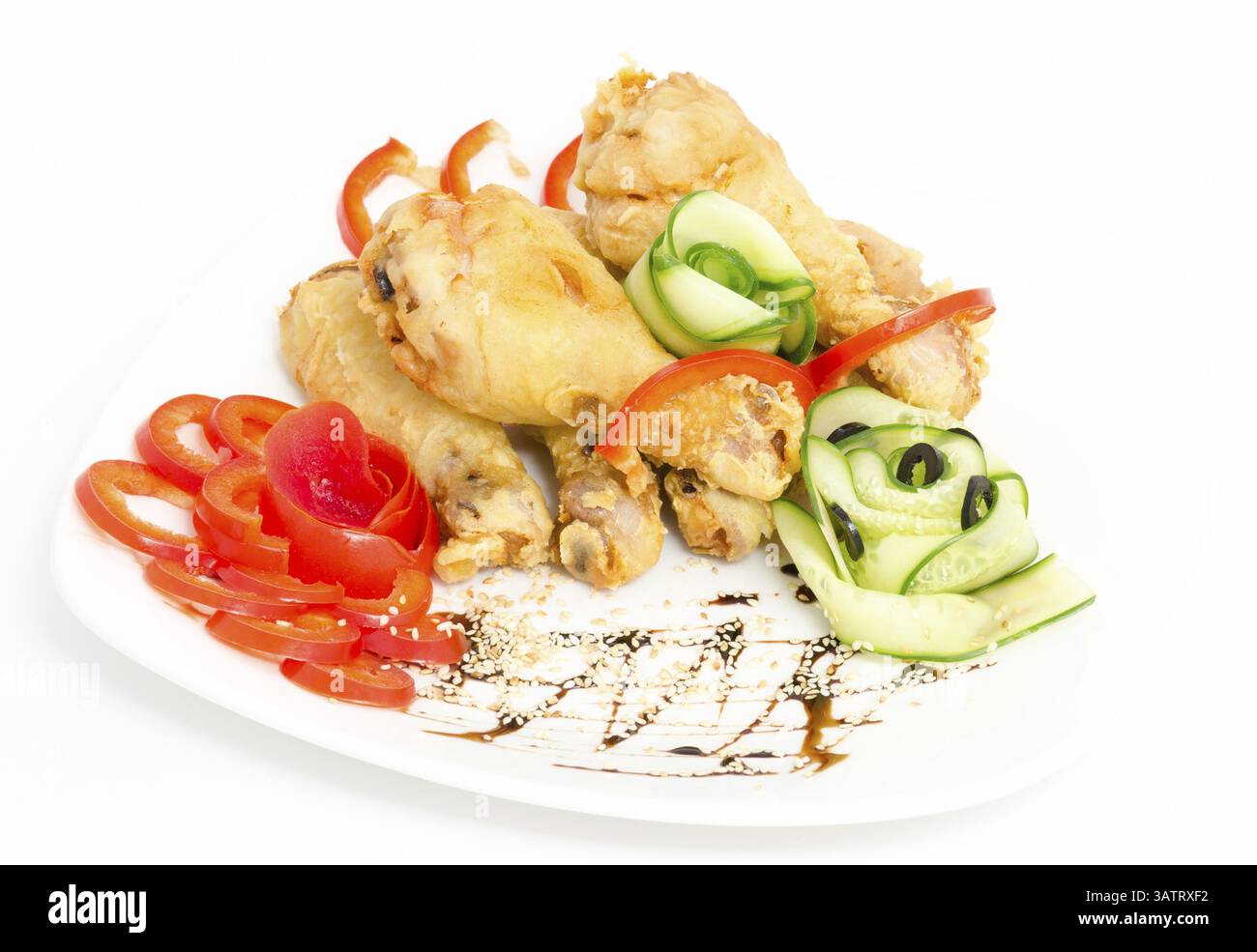 Gebratene Hähnchenschenkel, serviert mit rotem Pfeffer und Gurke Stockfoto