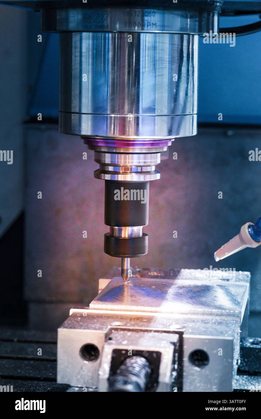 Die CNC-Fräsmaschine bohrt das Metallteil mit flachen Bohrwerkzeugen. Der Fertigungsbetrieb mit NC-Fräsmaschine. Stockfoto