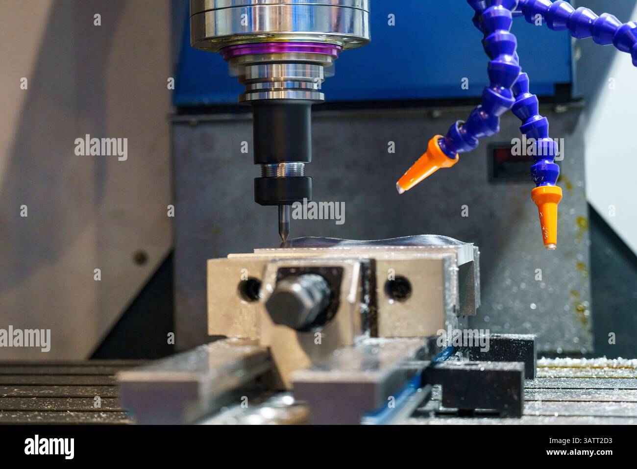 Die CNC-Fräsmaschine bohrt das Metallteil mit flachen Bohrwerkzeugen. Der Fertigungsbetrieb mit NC-Fräsmaschine. Stockfoto