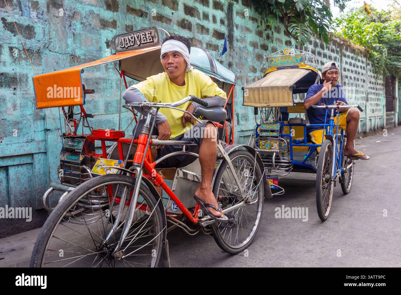 Pedikabfahrer warten am Straßenrand in Manila auf den Philippinen, um Passagiere durch die geschäftigen Straßen der Stadt zu transportieren Stockfoto
