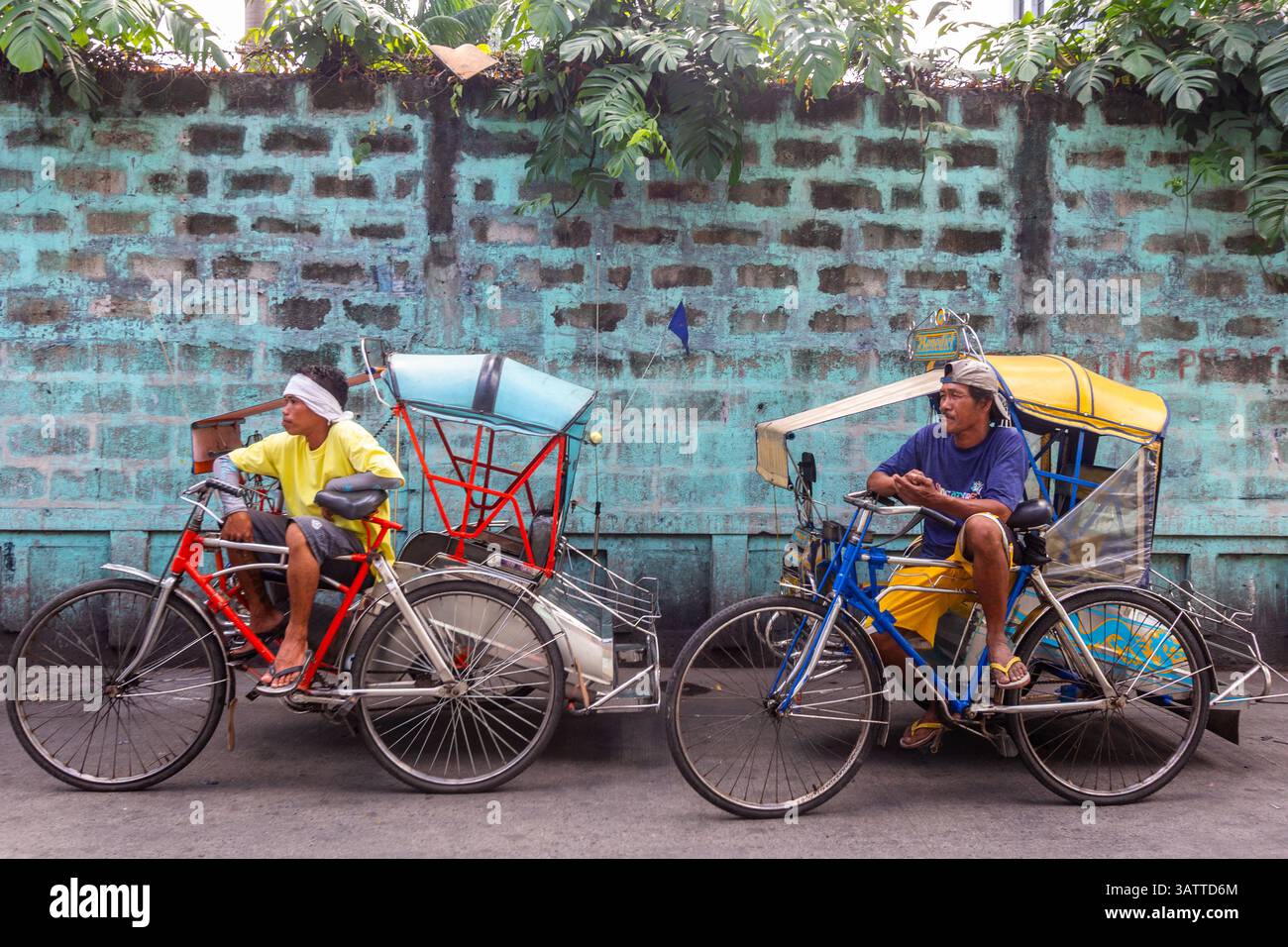 Pedikabfahrer warten am Straßenrand in Manila auf den Philippinen, um Passagiere durch die geschäftigen Straßen der Stadt zu transportieren Stockfoto