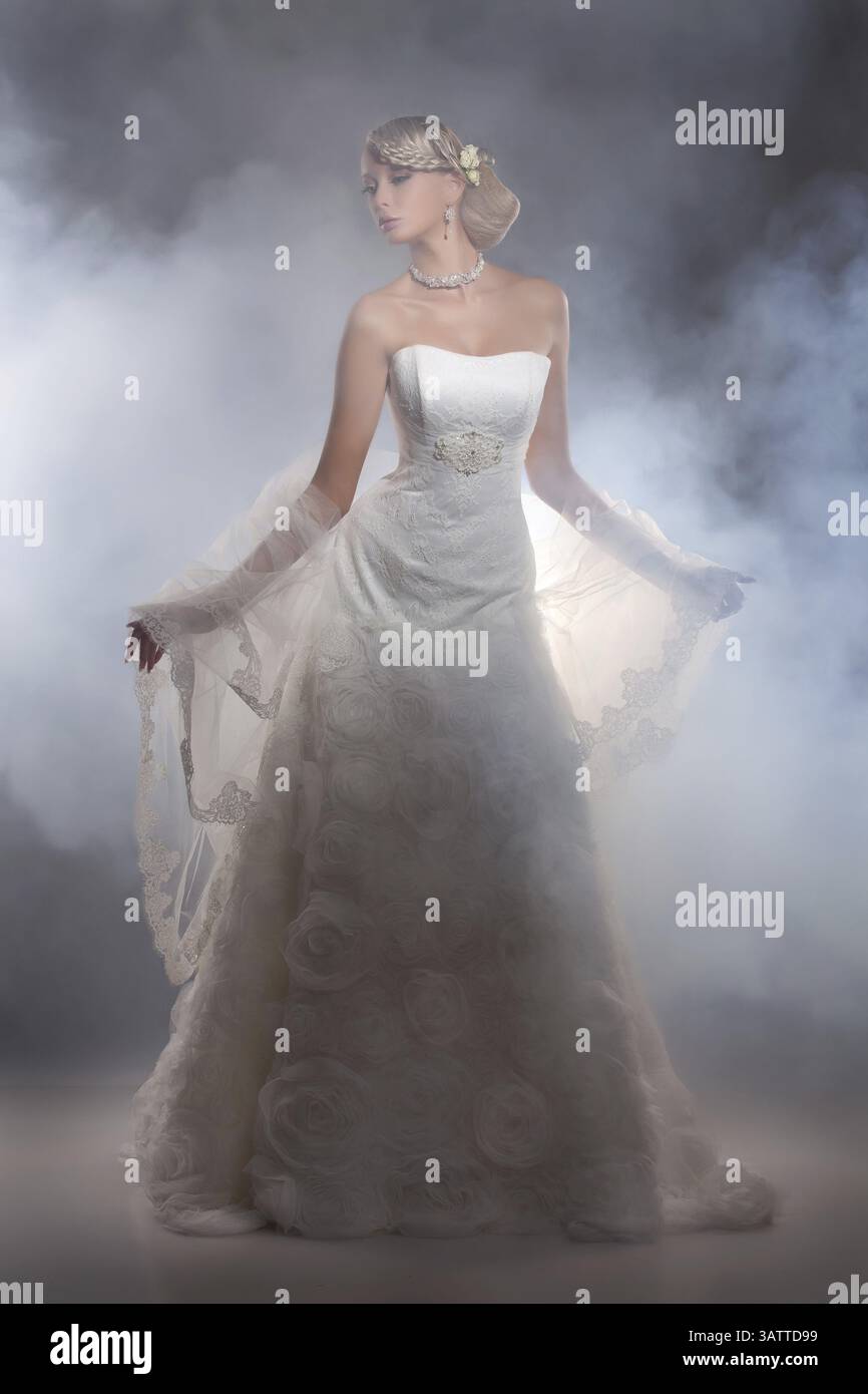 Junge schöne blonde Frau in einem Hochzeitskleid auf einem Atelierhintergrund Stockfoto