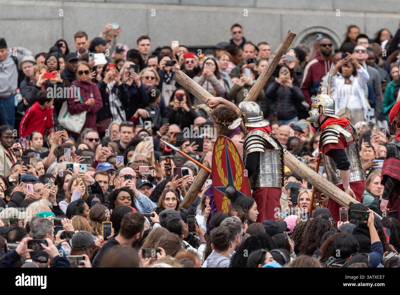 Jesus Christus, gespielt von Peter Bergin, trägt das Kreuzigungskreuz durch das Publikum während des Freiluftspiels Passion of Jesus auf dem Trafalgar Square Stockfoto
