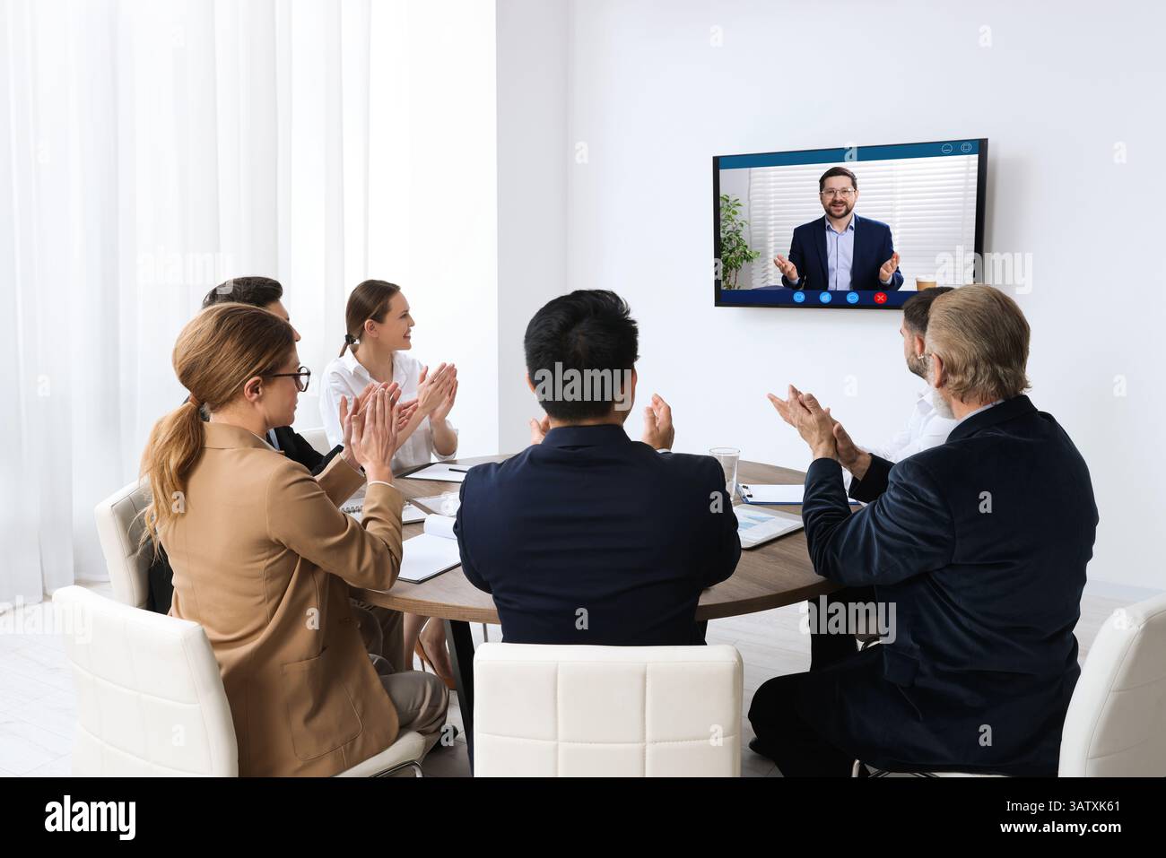 Redner, der über Online-Videochat an der Vorlesung teilnimmt. Publikum im Konferenzraum mit Fernseher Stockfoto