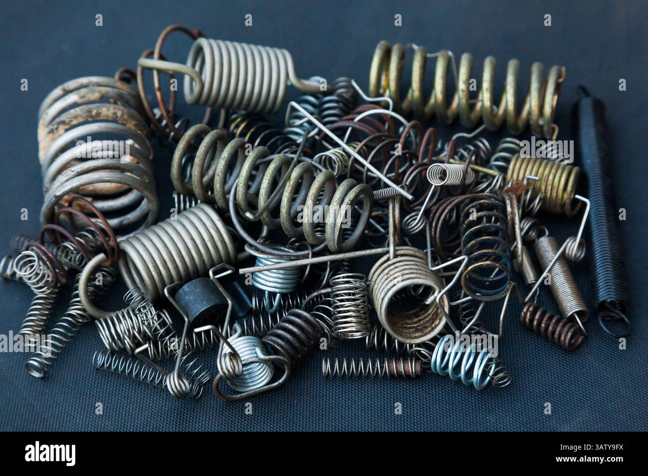 Viele kleine Federn unterschiedlicher Größe liegen auf einem Haufen vor schwarzem Hintergrund. Stockfoto