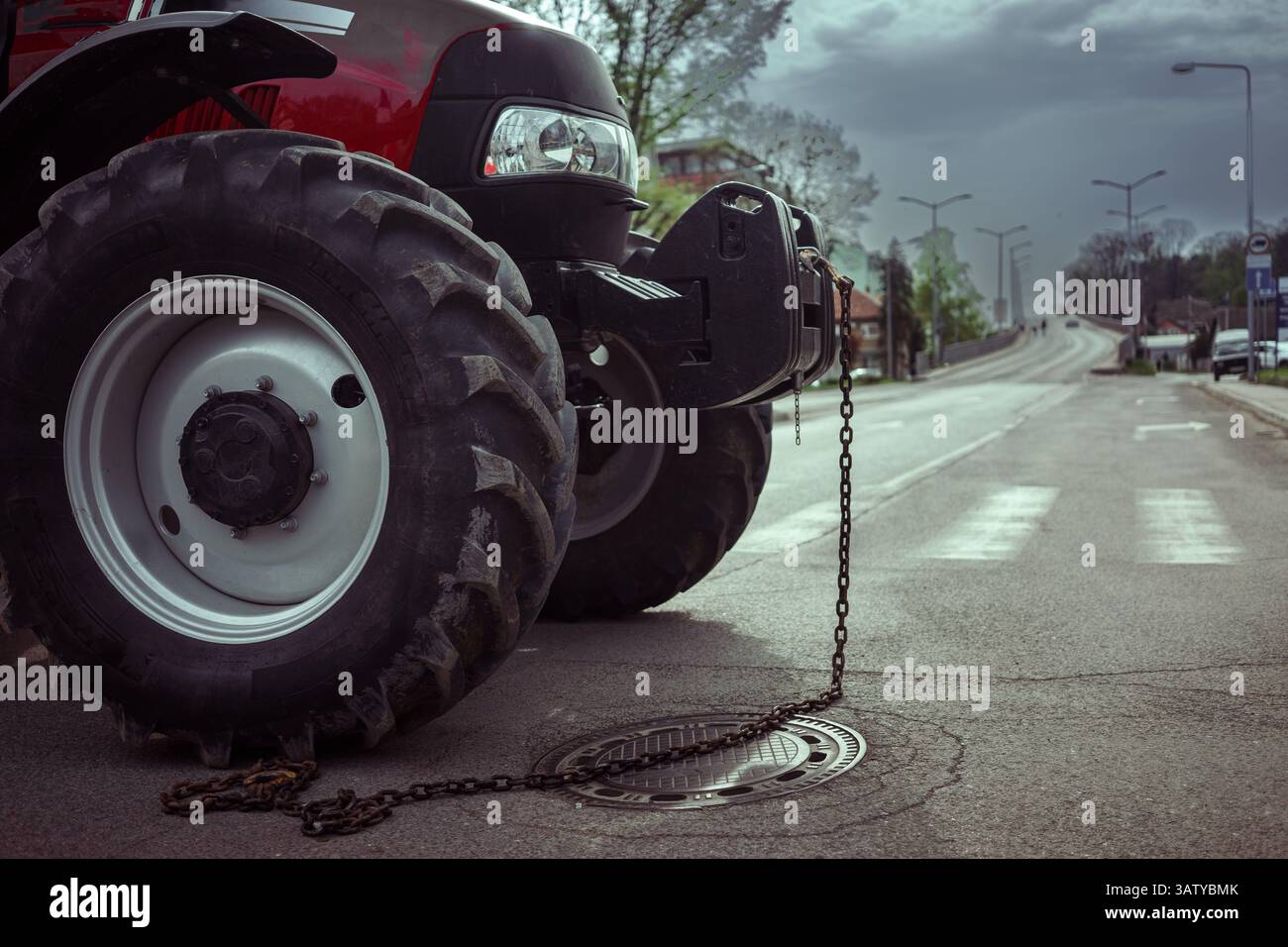 Detail eines großen Traktors mit Kette, der als Hindernis auf der Straße geparkt wurde, ein häufiges Ereignis bei politischen Protesten. Stockfoto