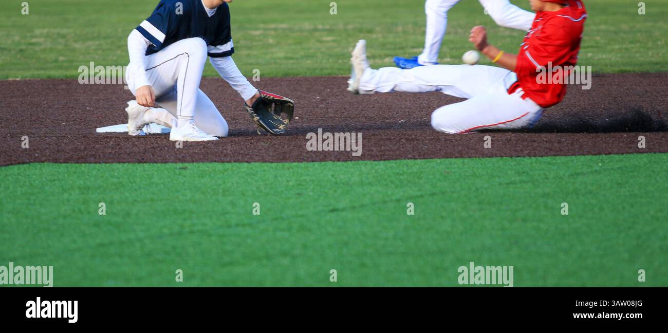 Ein High School Baseball Spieler rutscht in die zweite Base, während er die Basis während eines Baseballspiels stehlen will Stockfoto
