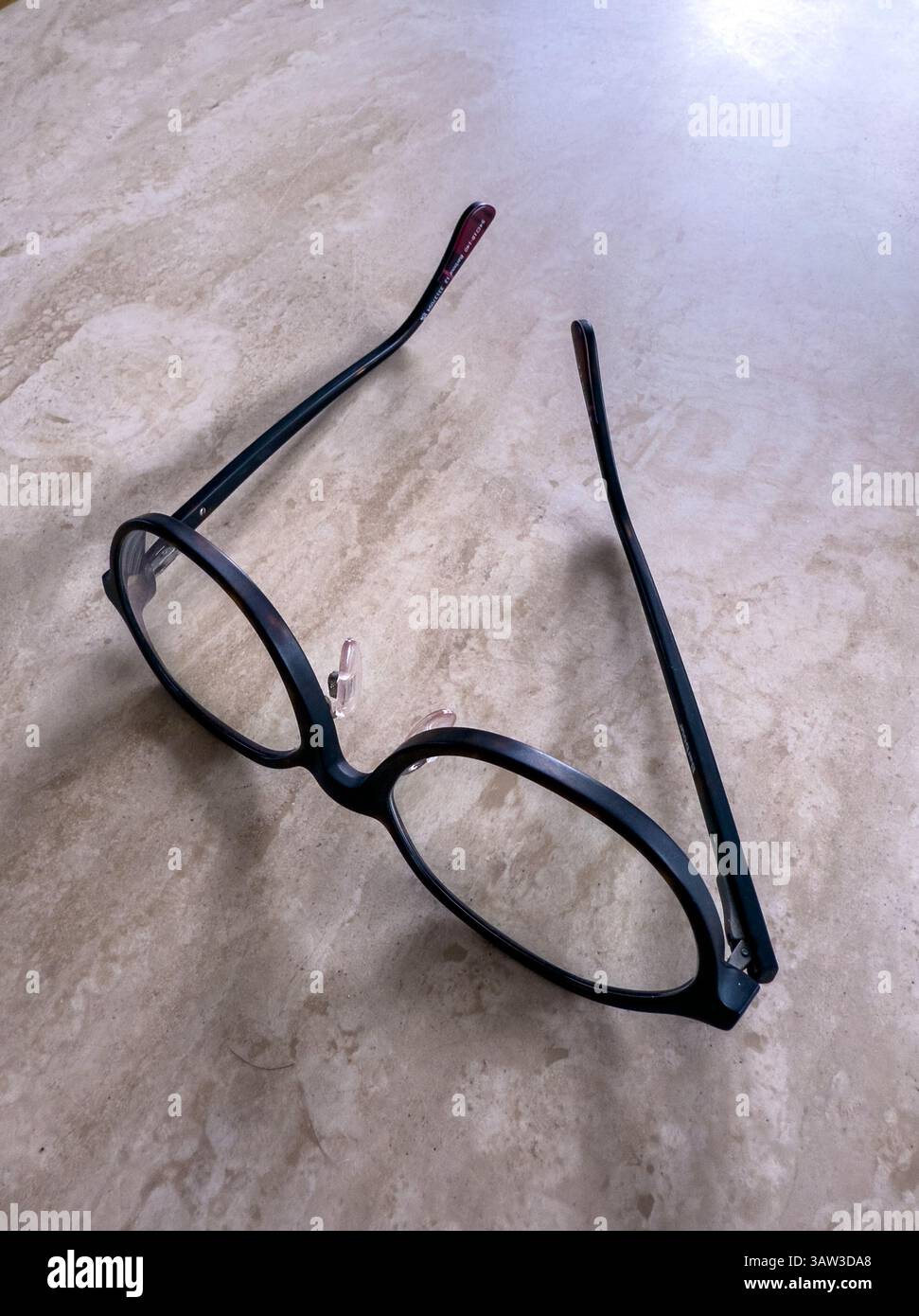 Eine Brille mit schwarzem Rand sitzt auf einem Tisch Stockfoto
