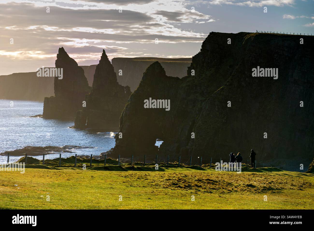 Die Stacks of Duncansby, Duncansby Head, Caithness, Schottland, Großbritannien. Drei Wanderer am Klippenrand im Vordergrund. Stockfoto