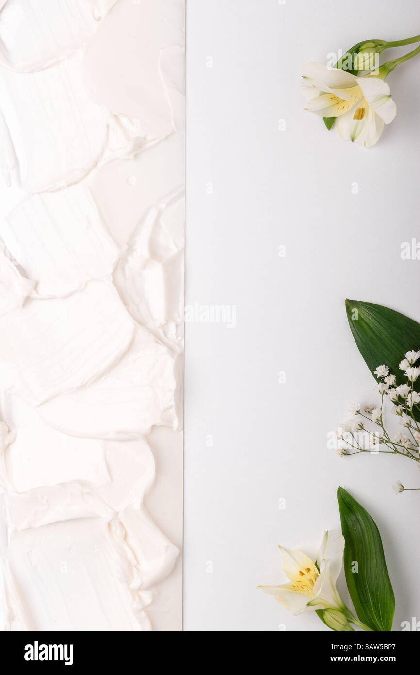 Weiße kosmetische Creme Textur Hintergrund mit Blumen. Cremiges Hautpflegeprodukt aus nächster Nähe. Stockfoto