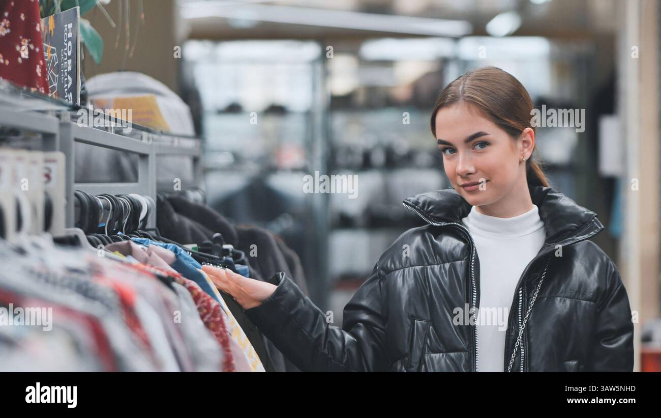 Modebewusste Frauen beim Einkaufen, die trendige Kleidung auswählen, während sie sich auf die Kleidung bewegen, werden in der Einzelhandelsboutique ausgestellt Stockfoto
